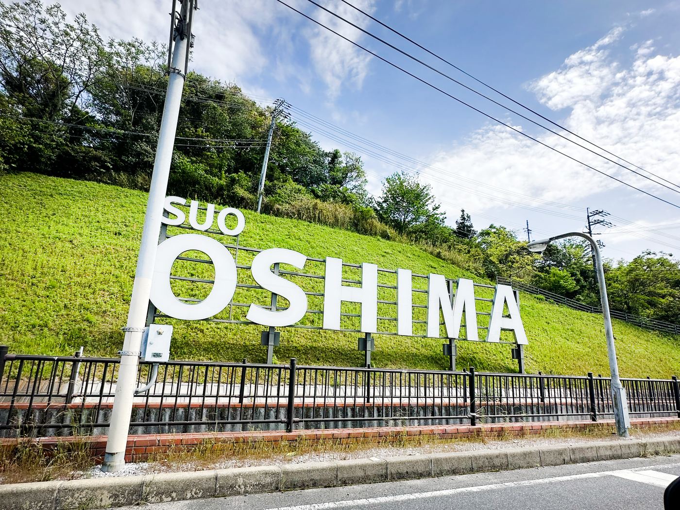 山の斜面に立つ「SUO OSHIMA」の大きな文字